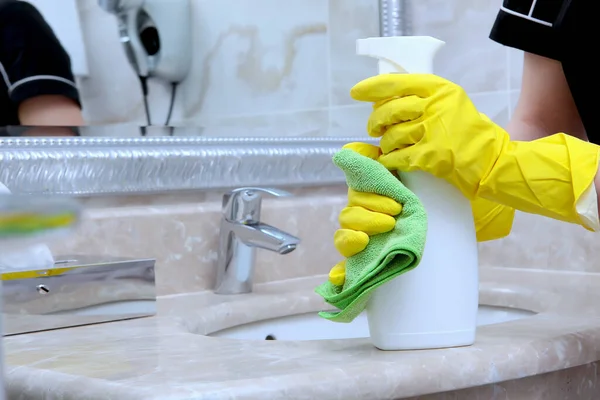 An employee of the cleaning service at the hotel washes and disinfects the bathroom. Unrecognizable photo. Copy of the space. — Stock Photo, Image