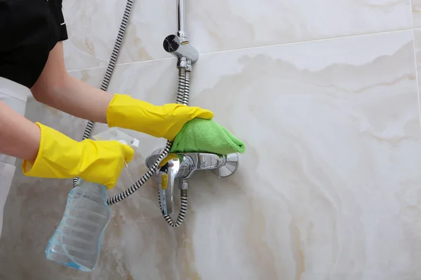 Las manos en guantes de goma amarillos lavan el grifo en el puesto de ducha. Fotografía irreconocible.Limpieza en el hotel o en casa . — Foto de Stock