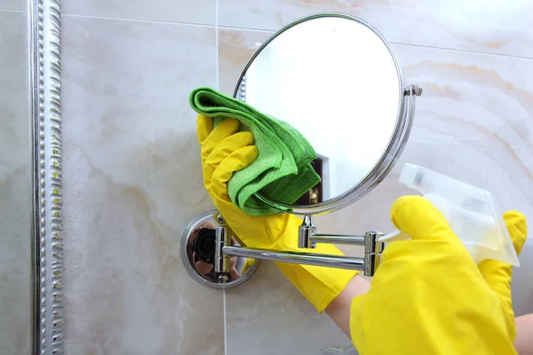 Las manos en guantes de goma amarilla limpian el espejo de la pared en el baño. Foto irreconocible. El concepto de limpieza y limpieza . — Foto de Stock