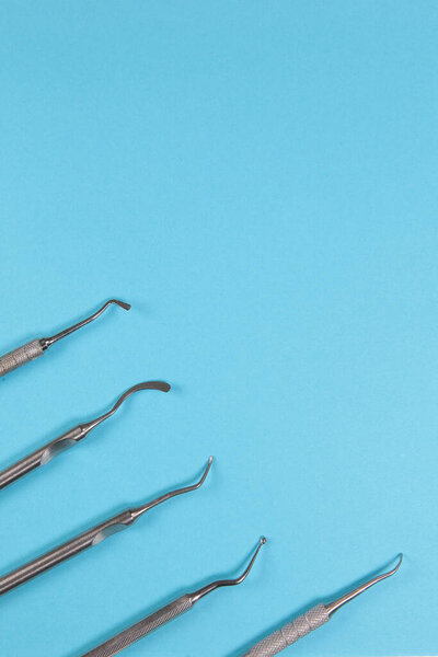 Dental instruments for the treatment and filling of teeth on a blue background. Vertical photo.