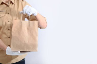 Servis teslimatı konsepti. Beyaz eldivenli erkek eller kese kağıdı tutuyor. Reklam alanı. Boşluğun kopyası.