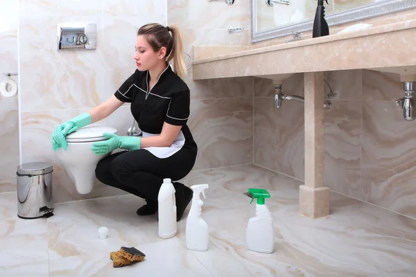制服を着た女性がバスルームのトイレを洗う ホテルや家庭での清潔感と消毒の概念 スペースのコピー — ストック写真
