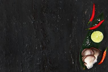 Siyah desenli arka planda baharatlı Cayenne biberli istiridye mantarları. Üst Manzara. Boşluğu kopyala.