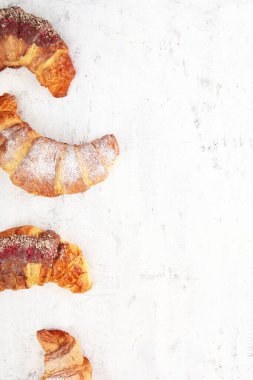 Hafif desenli arka planda birkaç farklı kruvasan. Dikey fotoğraf. Üst Manzara. Boşluğu kopyala.