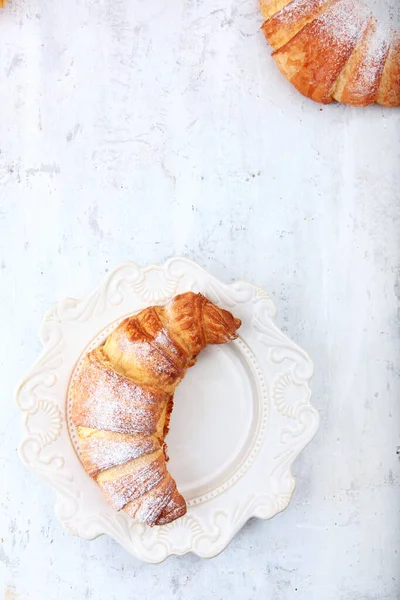 Croissant Uma Placa Branca Polvilhado Com Açúcar Texturizado Fundo Madeira — Fotografia de Stock