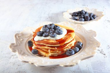 Beyaz desenli tabakta yaban mersinli krep ve krema sosu. Hafif bir arkaplanda yatay fotoğraf. Üst Manzara. Boşluğu kopyala.