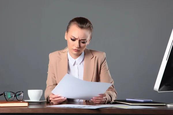 Hüsrana uğramış bir iş kadını masasında oturup basılı bir belgeye bakar. Finansal kriz kavramı. Olumsuz duygu. Boşluğu kopyala.