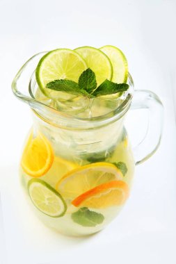 Limonata portakal ve limon dilimlerinden yapıldı. Beyaz arka planda uzun cam bir sürahi içinde nane şekeri ile. İzole bir nesne. Boşluğu kopyala.