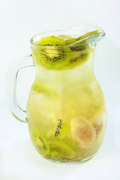 Limonada de fatias de kiwi e banana com gelo em um jarro de vidro alto em um fundo branco. Um objecto isolado. Foto vertical. Vista superior . — Fotografia de Stock