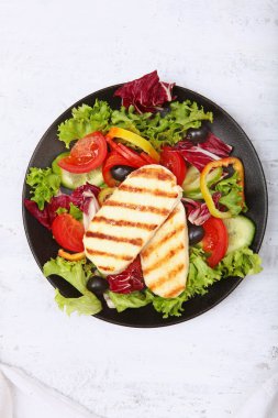 Sebzeli salata ve siyah tabakta ızgara peynir. Uzayı kopyala Üst görünüm.