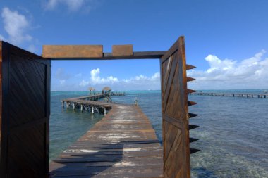 Karayip Denizi üzerinde uzanan ahşap iskele. Karayip okyanusuna bakan açık kapılar