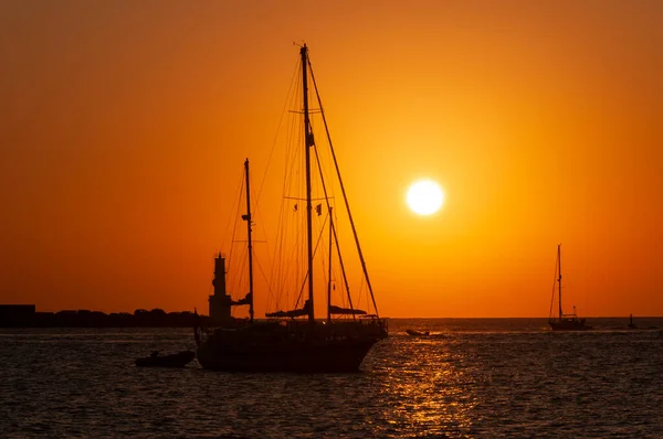 Sunset light on the sea with the silhouette of boats and lighthouse. Mediterranean sea Formentera island Spain