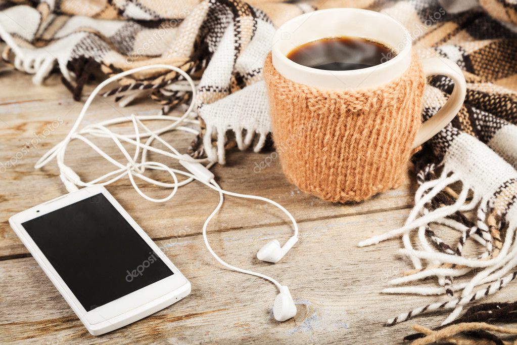 Hot coffee in a large cup, mobile phone with headphones