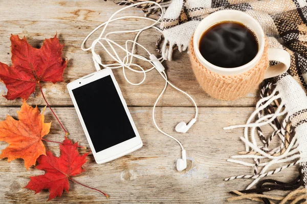 Hett kaffe i en stor kopp, mobiltelefon med hörlurar — Stockfoto