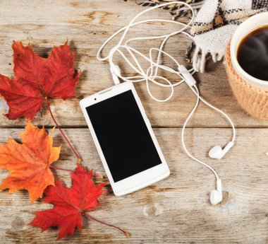 Cep telefonu kulaklık ile büyük bir fincan sıcak kahve