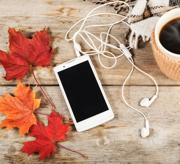 Café caliente en una taza grande, teléfono móvil con auriculares —  Fotos de Stock