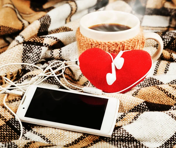 Ζεστό καφέ, λευκό κινητό τηλέφωνο με ακουστικά, μαλακή κόκκινη καρδιά — Φωτογραφία Αρχείου