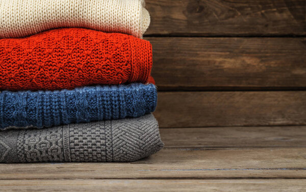 Multicolored sweaters stacked on a wooden surface