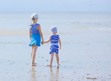 Mesafe içine arayan sahil üzerinde çizgili giysili iki kız kardeşi