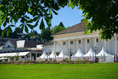 Baden-Baden Kumarhanesi manzarası, yaz şenlikleri sırasında beyaz çadırlı Kurhaus adını verdi. Ön planda çimenlik. Üst taraftaki ağaçlardan yeşil yapraklar. Baden-Wuerttemberg, Almanya. 