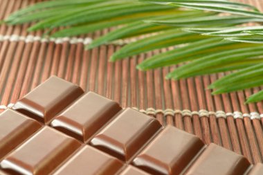 Kahverengi bambu seti üzerine çikolata ve palmiye yaprağı konur..