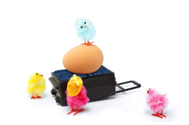 Yumurtalı, hasır şapkalı ve tatile çıkmaya hazır bavullu dört renkli Paskalya pilici. Beyaz arka planda izole edilmiş. Paskalya tatili konsepti.