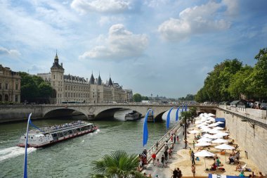 Paris-Plages kumsalları Seine nehri kıyısında. Gezi tekneleri, Pont au Change köprüsü, soldaki Conciergerie ve sağdaki buketler. Paris, Fransa.