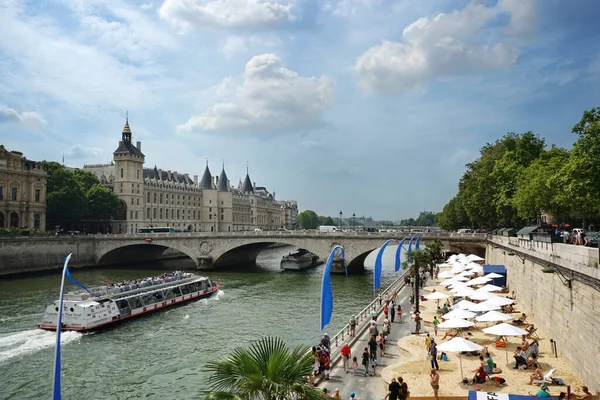 Paris-Plages kumsalları Seine nehri kıyısında. Gezi tekneleri, Pont au Change köprüsü, soldaki Conciergerie ve sağdaki buketler. Paris, Fransa.