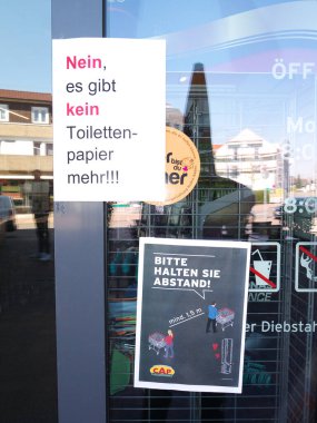 Corona virüsü döneminde süpermarketin giriş kapısı önleme uyarısı. Mesafeni koru ve tuvalet kağıdı kullanma. Almanya.