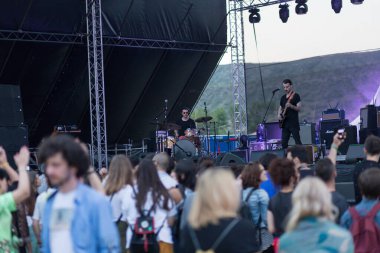 Tiflis Açık Hava 2019. Bir müzik festivalinde seyirciler ellerini kaldırdı ve sahnenin üstünden ışıklar süzülüyor. Yumuşak odak, yüksek ISO, taneli görüntü.