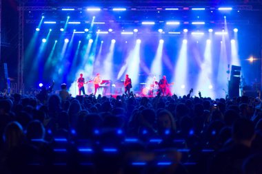 Tiflis Açık Hava 2019. Bir müzik festivalinde seyirciler ellerini kaldırdı ve sahnenin üstünden ışıklar süzülüyor. Yumuşak odak, yüksek ISO, taneli görüntü.