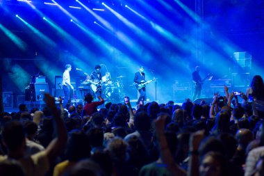 Tiflis Açık Hava 2019. Bir müzik festivalinde seyirciler ellerini kaldırdı ve sahnenin üstünden ışıklar süzülüyor. Yumuşak odak, yüksek ISO, taneli görüntü.