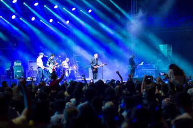 Tiflis Açık Hava 2019. Bir müzik festivalinde seyirciler ellerini kaldırdı ve sahnenin üstünden ışıklar süzülüyor. Yumuşak odak, yüksek ISO, taneli görüntü.