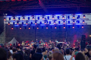 Seyirci bir Müzik Festivali ve sahne yukarıdan aşağı akış ışıklar kaldırdı elleriyle. Yumuşak odak, yüksek ISO, grenli görüntü.