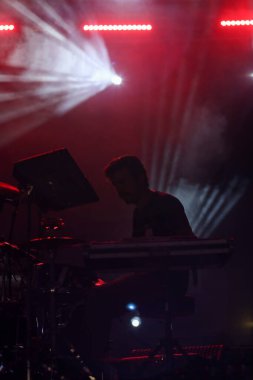 Seyirci bir Müzik Festivali ve sahne yukarıdan aşağı akış ışıklar kaldırdı elleriyle. Yumuşak odak, yüksek ISO, grenli görüntü.