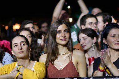 Seyirci bir Müzik Festivali ve sahne yukarıdan aşağı akış ışıklar kaldırdı elleriyle. Yumuşak odak, yüksek ISO, grenli görüntü.