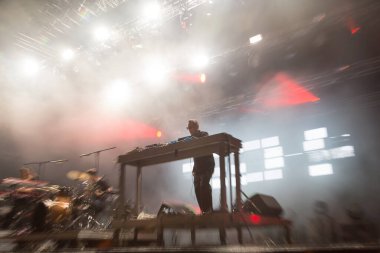 Seyirci bir Müzik Festivali ve sahne yukarıdan aşağı akış ışıklar kaldırdı elleriyle. Yumuşak odak, yüksek ISO, grenli görüntü.