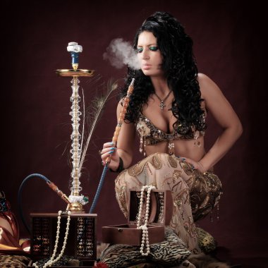 Stüdyoda Burgundy arka planında Doğulu kızların portresi nargile tüttürüp dans ediyor.