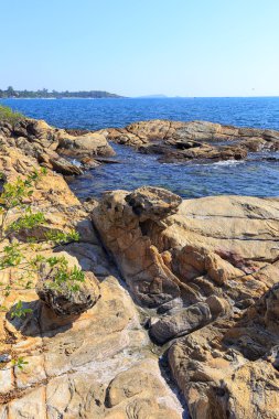 Güneşli bir günde Tayland açıklarında deniz manzaralı kayalık kıyı ve mavi su