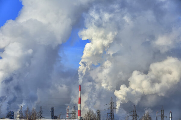 industrial landscape smoke from the chimneys large plant and power lines against the blue sky in winter