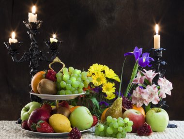 Karanlık bir arka plan stüdyosundaki çeşitli olgun meyvelerin ve narin çiçeklerin zarif hayatları.