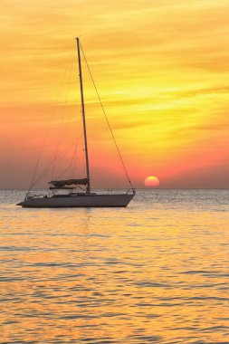 Deniz manzaralı gün batımı ve Tayland kıyılarında sönük yelkenli bir tekne.