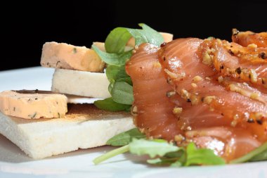 Kızarmış ekmek, füme kırmızı balık ve beyaz tabak stüdyosunda yeşillikler.