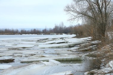 Baharın başlarında bulutlu bir günde nehir üzerindeki buz tabakası sürükleniyor.