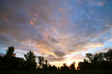 Yaz manzarası dramatik bulutlar gün batımında çayır üzerinde ve yağmurdan sonra gökkuşağı
