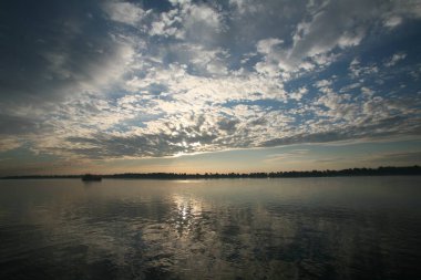 güzel yaz manzarası güzel gün batımı nehir üzerinde, güzel bulutlar ve ağaçlar kıyıda.