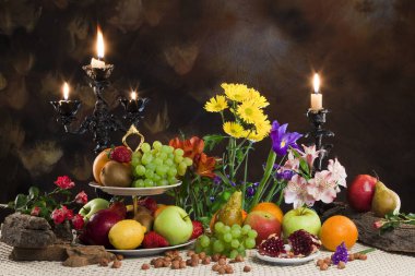 Karanlık bir arka plan stüdyosundaki çeşitli olgun meyvelerin ve narin çiçeklerin zarif hayatları.