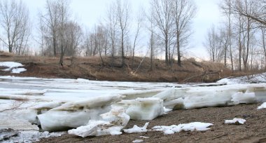 Baharın başlarında bulutlu bir günde nehir üzerindeki buz tabakası sürükleniyor.