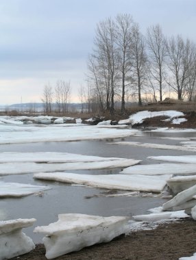 Baharın başlarında bulutlu bir günde nehir üzerindeki buz tabakası sürükleniyor.