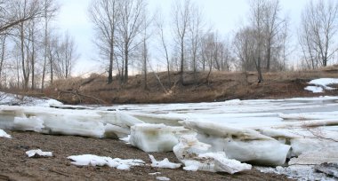 Baharın başlarında bulutlu bir günde nehir üzerindeki buz tabakası sürükleniyor.